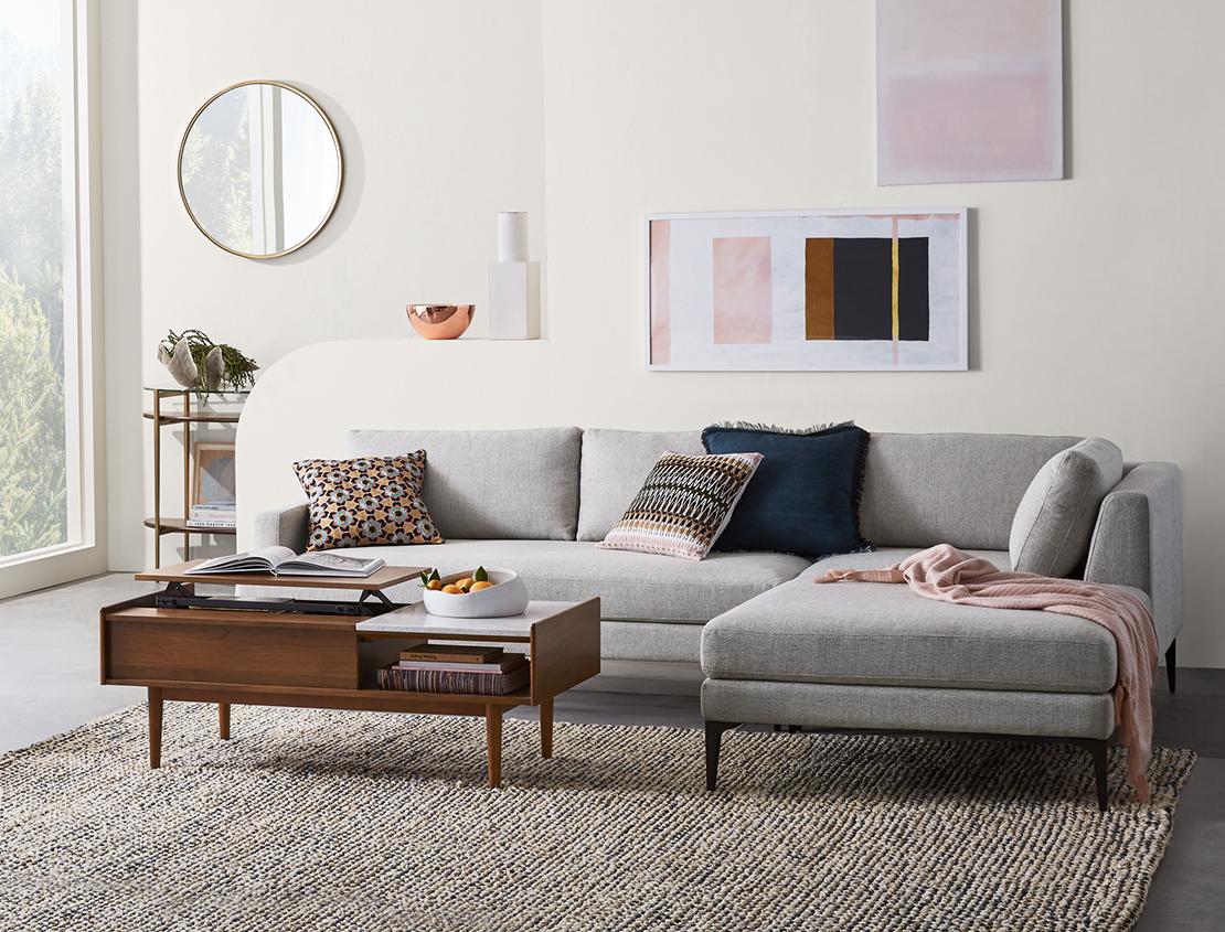 Shop West Elm — Modern Furniture, Home Décor, Lighting & More | Featuring Andes Reversible Grey Sectional Sofa and Mid-Century Pop-Up Storage Dark Brown Coffee Table in decorated living room.